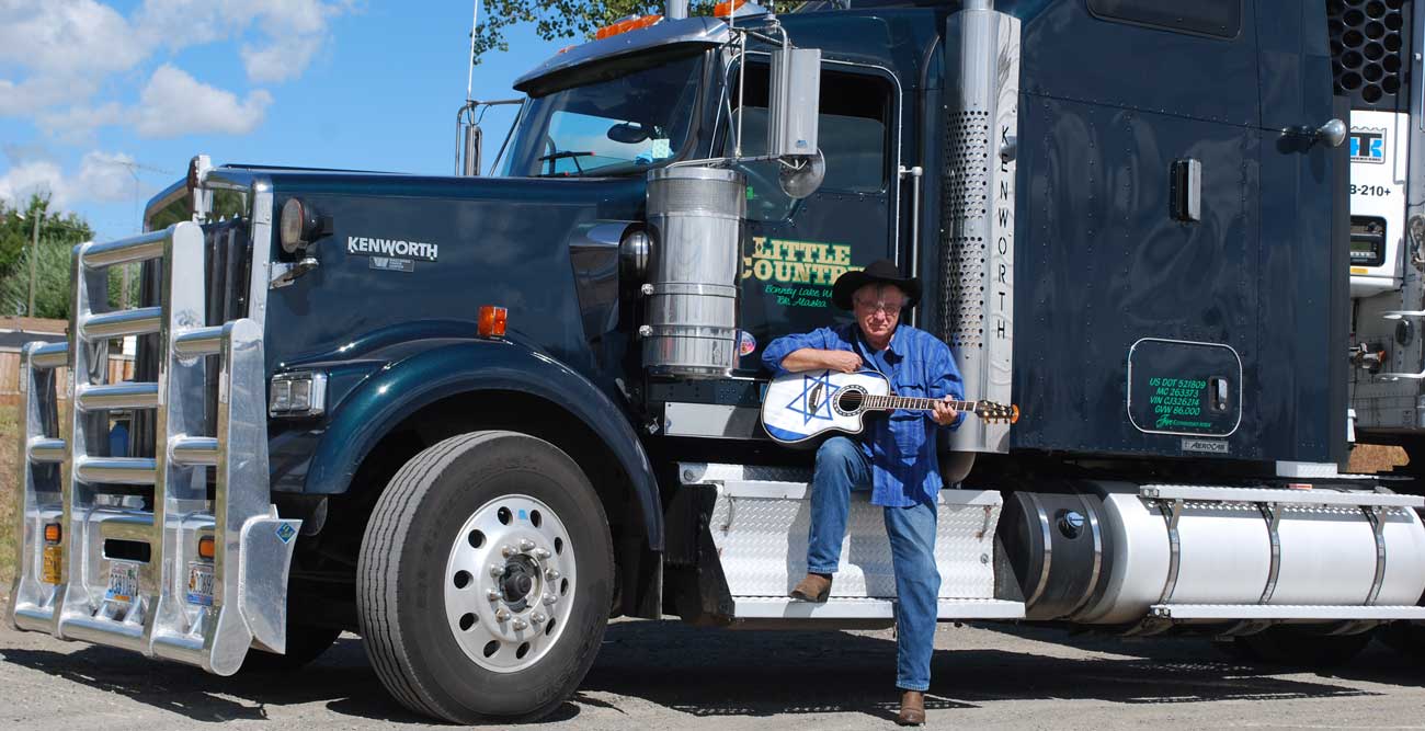 Singin' Sam playing guitar by his truck